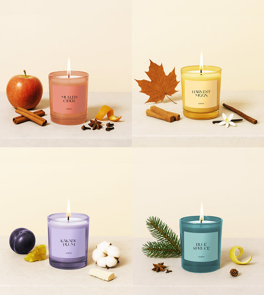 Four candles of different colors with decorative items on a light background