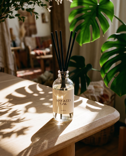 Diffuser bottle labeled 'Smoked Oak' on a wooden surface with plants in the background